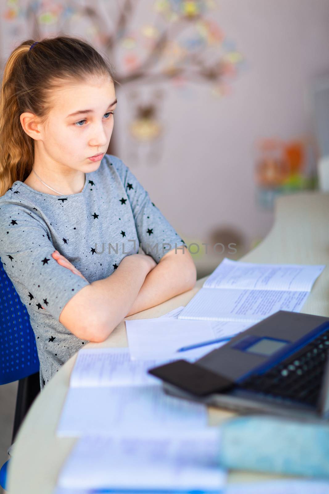 Beautiful young school girl working at home in her room with a laptop and class notes studying in a virtual class. Distance education and learning, e-learning, online learning concept during quarantine