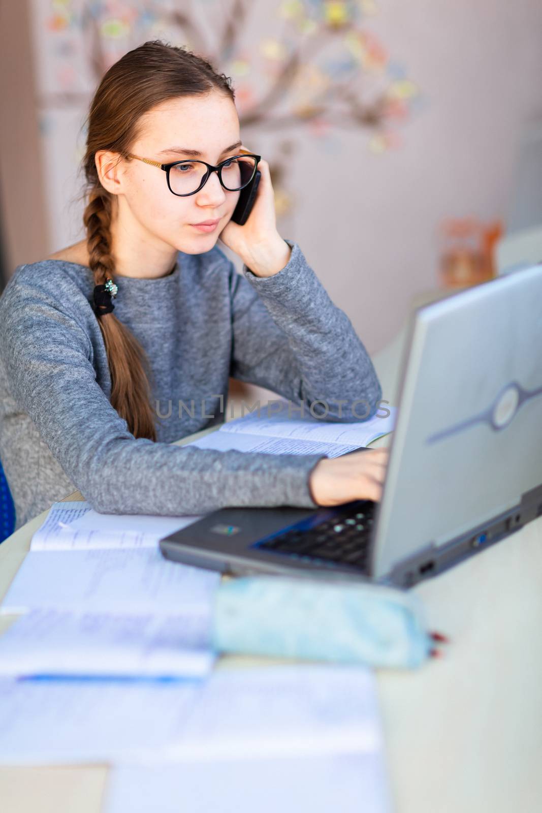 Beautiful young school girl working at home in her room with a laptop and class notes studying in a virtual class. Distance education and learning, e-learning, online learning concept during quarantine