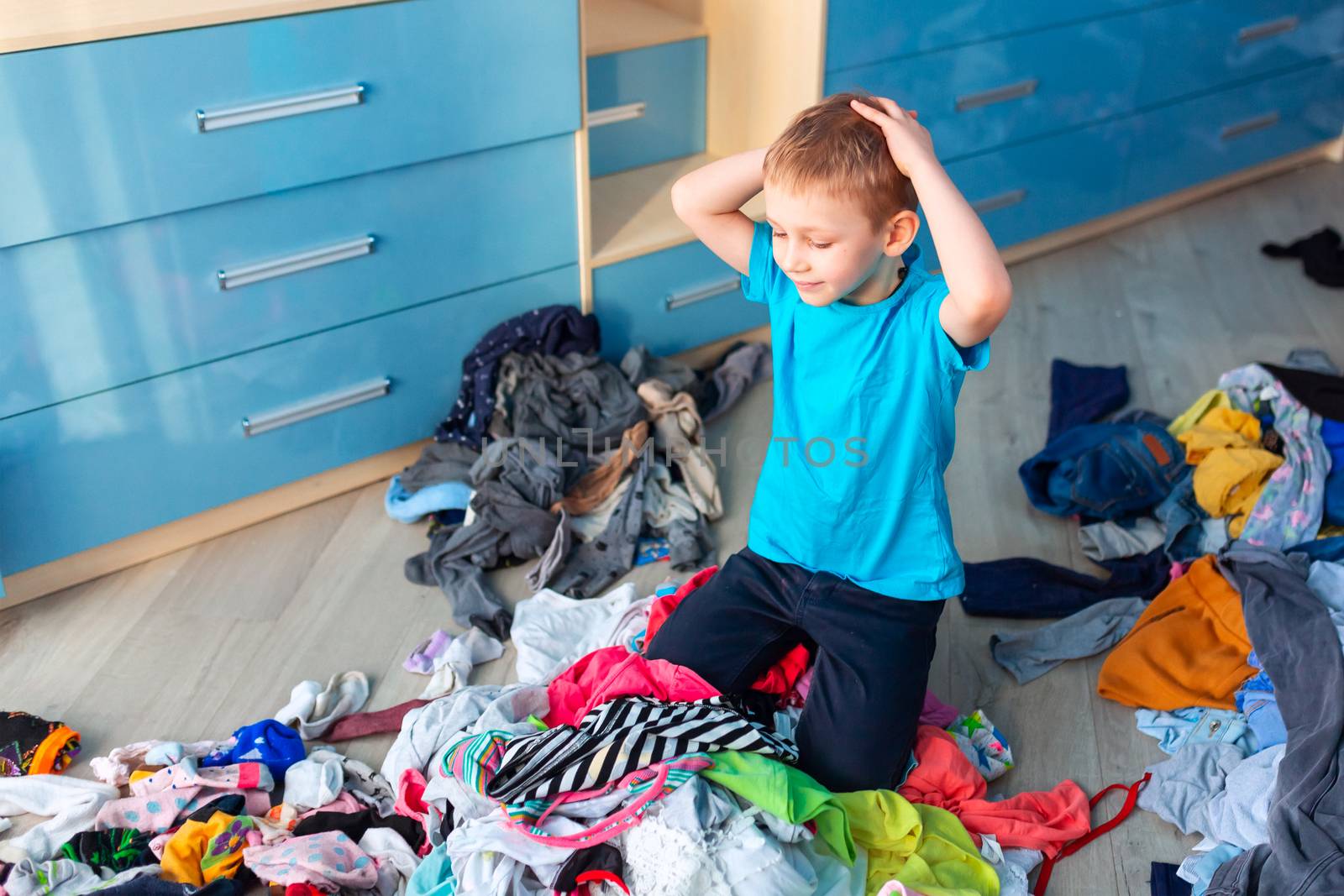 Small boy desperate with the mess in his clothes in his bedroom.
