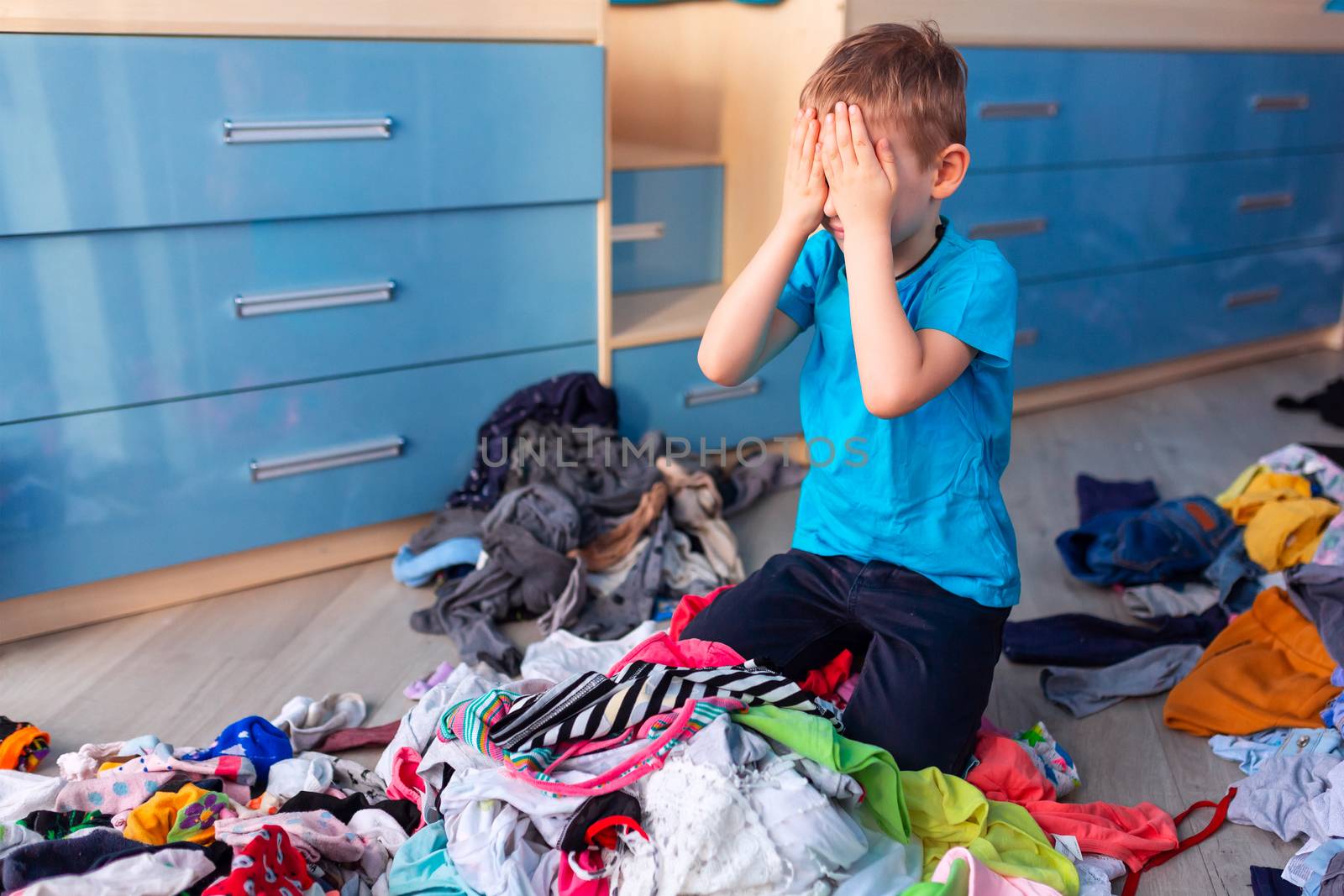 Small boy desperate with the mess in his clothes in his bedroom.