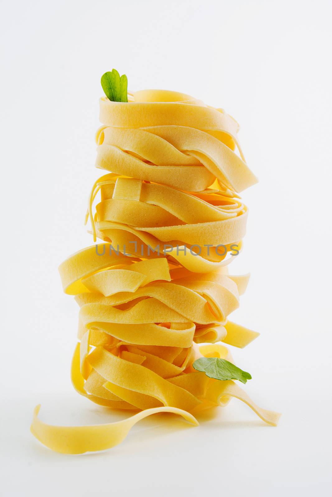 Stacked tagliatelle raw pasta nest egg to dry,
on isolated background, vertical image