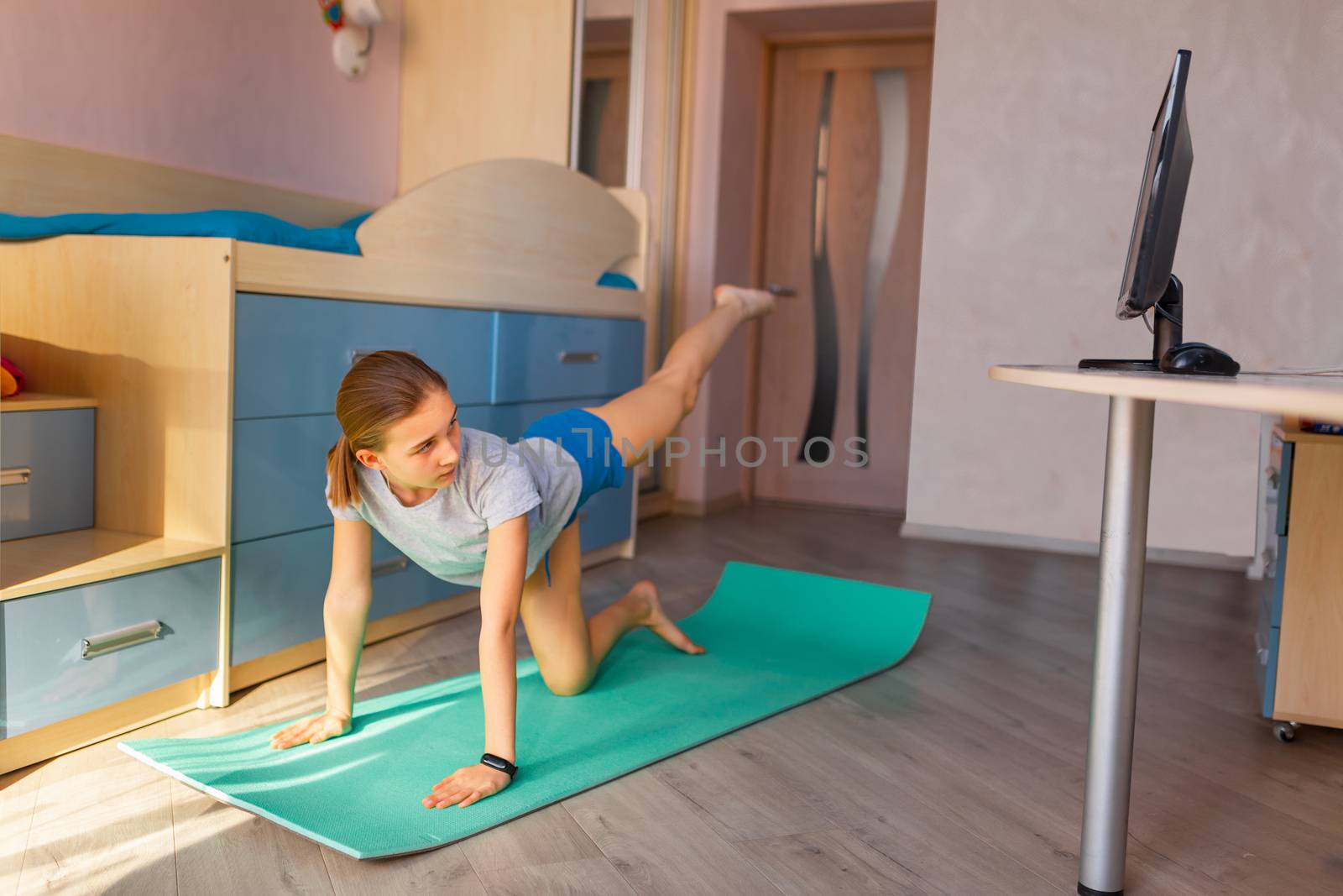 Tennage girl doing fitness gymnastics at home. Gymnastics video tutorial. Gymnastic exercises. Children's activity in quarantine during coronavirus pandemic concept