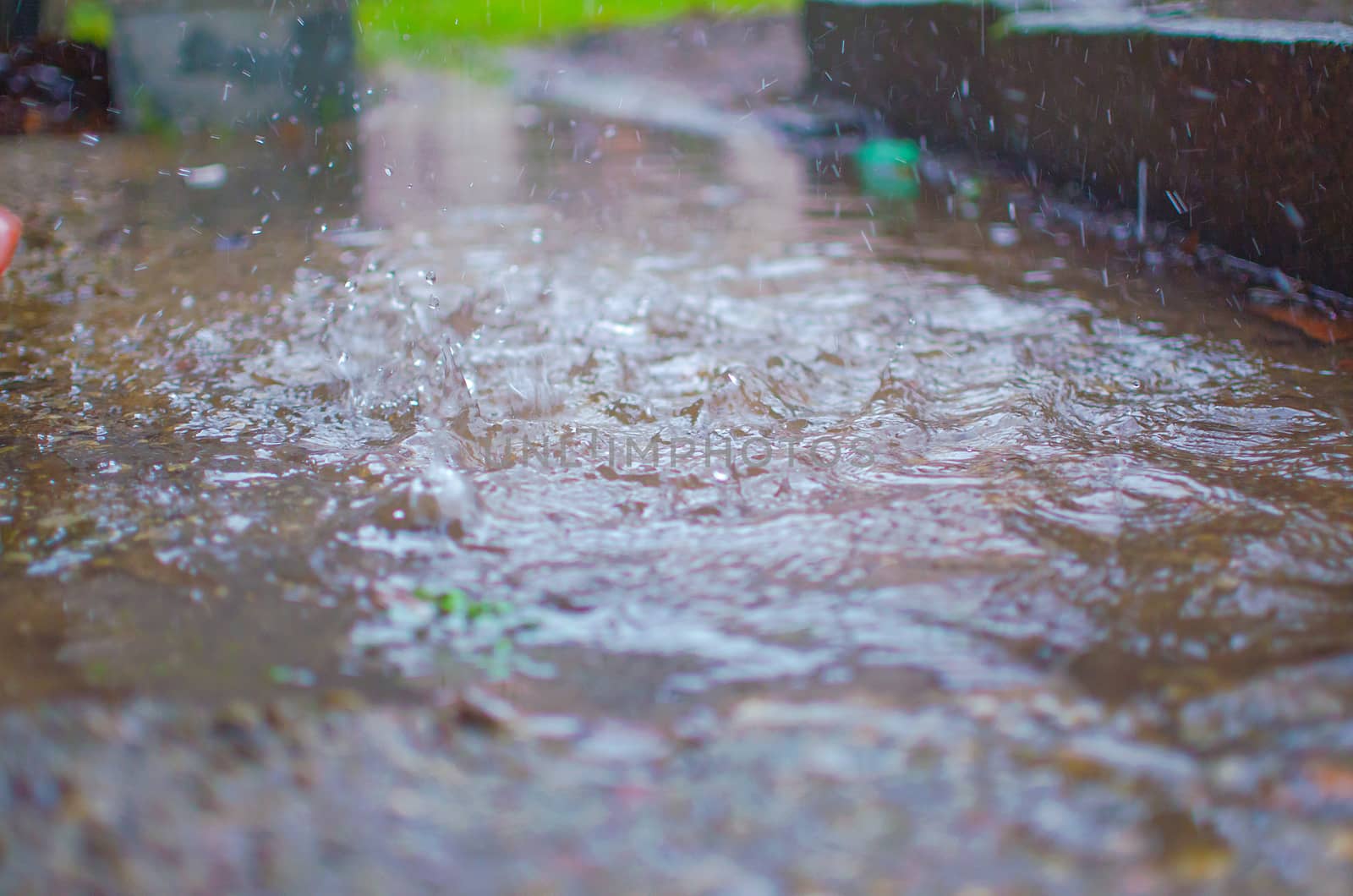 Drops of heavy rain on sidewalk surface. Rain water on the surface of the flood the sidewalk on the city street.