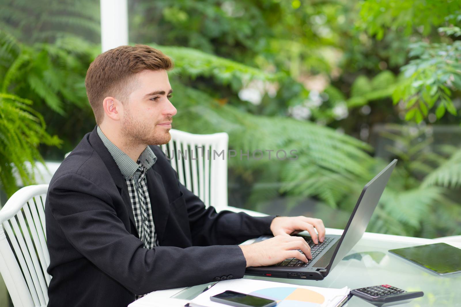 businessman and smiling, as he work on his laptop in the living room.