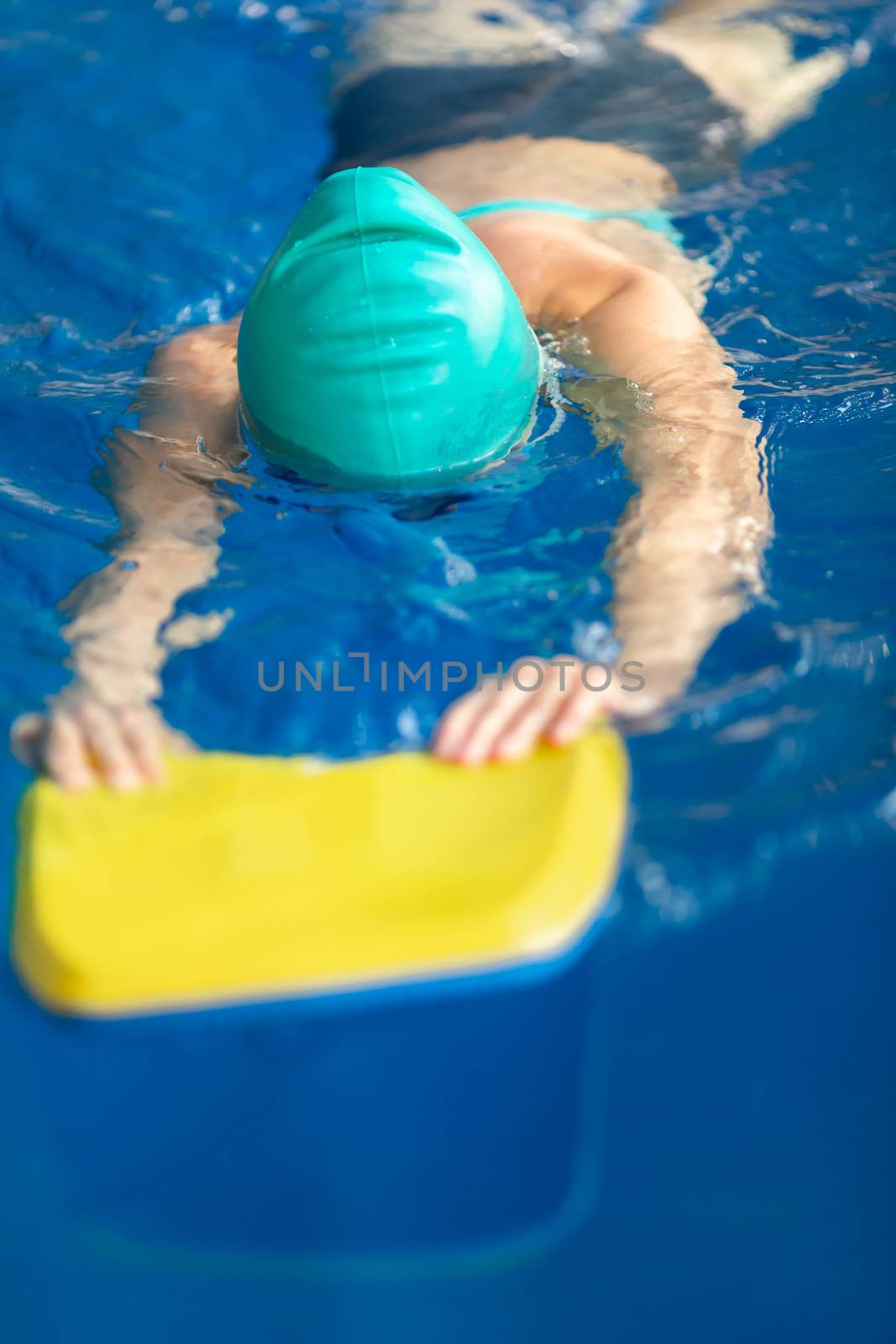 Cute little girl training in a swimming pool. Swimming sport for kids concept
