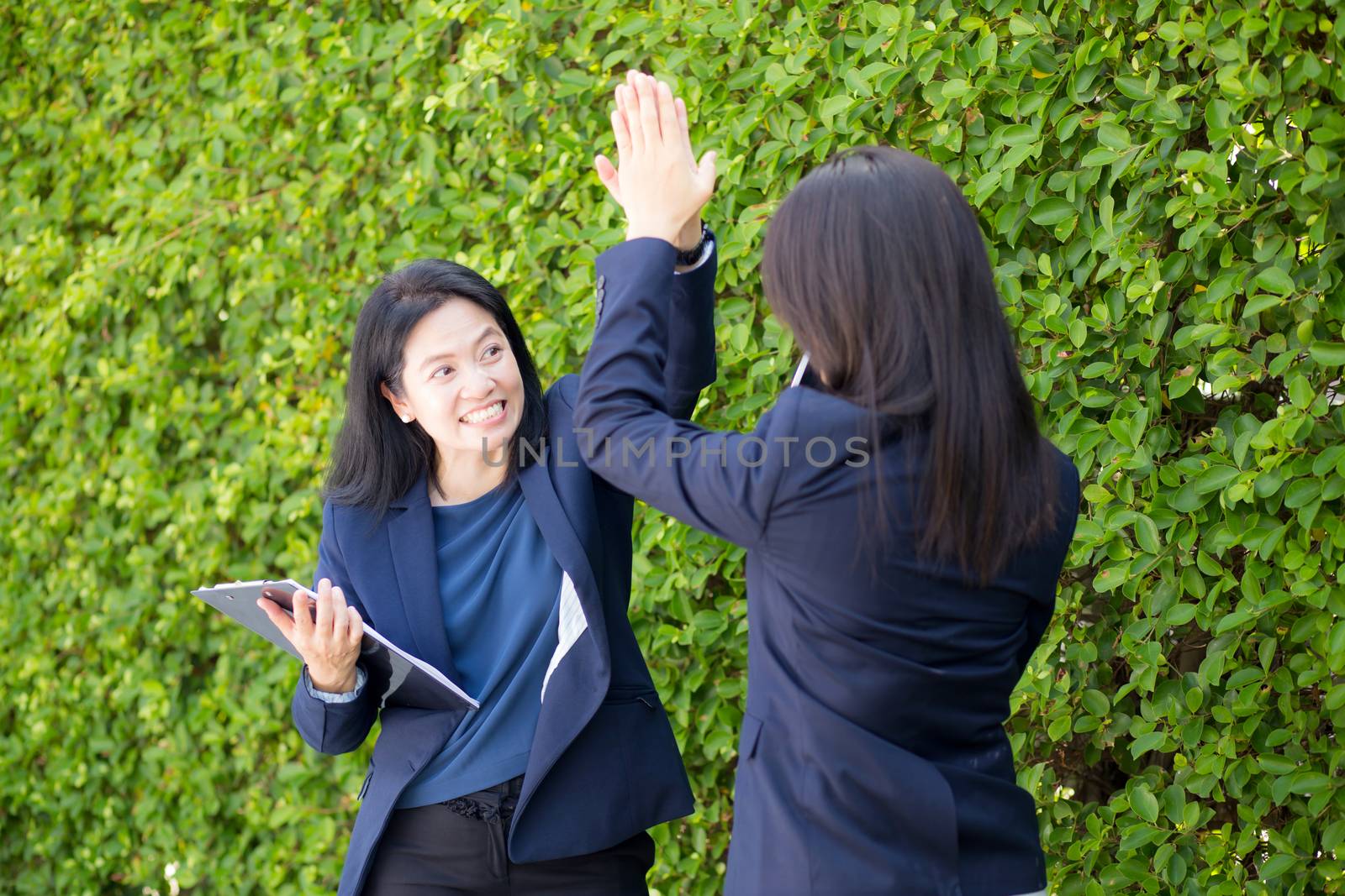 Businesswoman two people high fiving outdoors nature background. by nnudoo