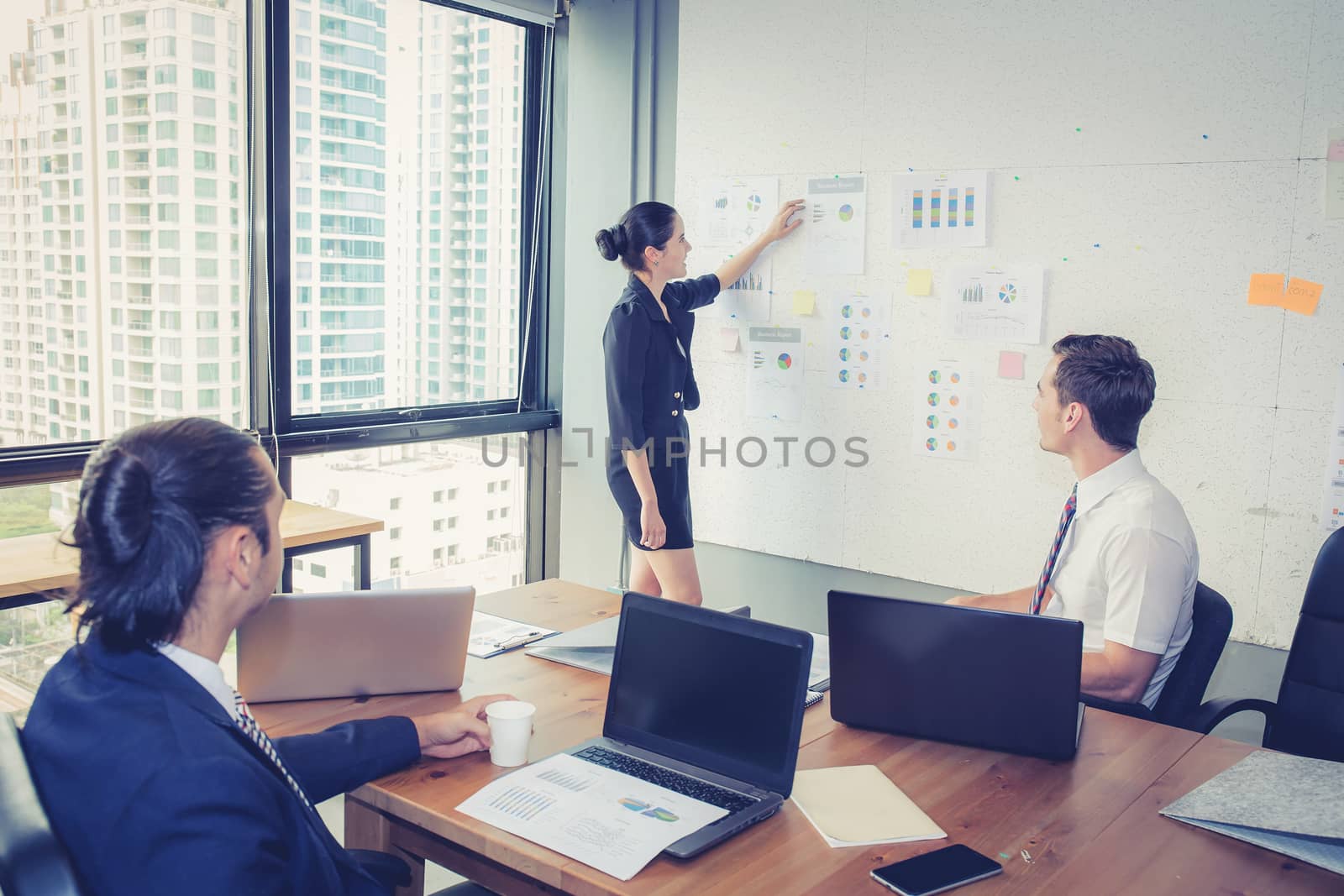 Three business people in modern office looking report and analyz by nnudoo