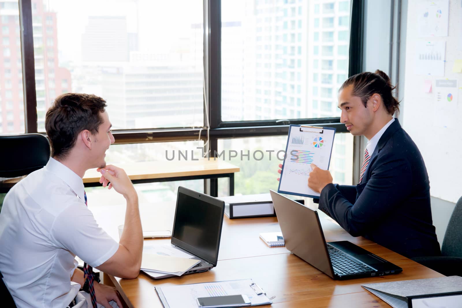 Business people discussing the charts and graphs showing the results of their successful teamwork in meeting room.