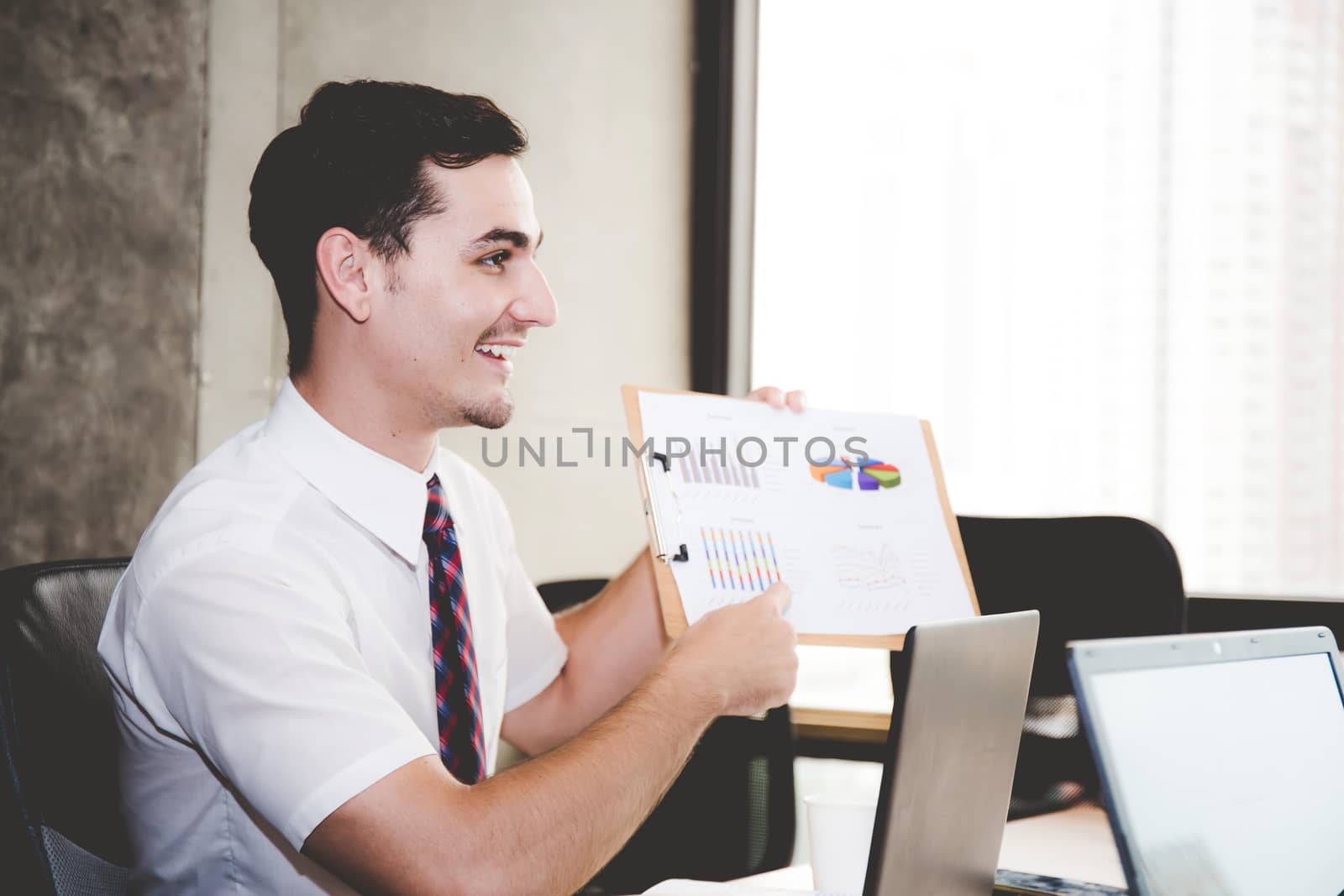 Business people discussing the charts and graphs showing the results of their successful teamwork in meeting room.