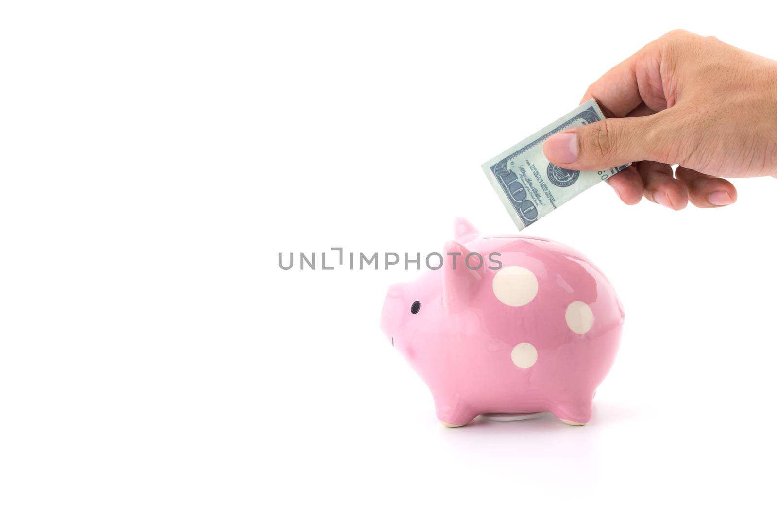 male hand saving money in a piggybank on white background.