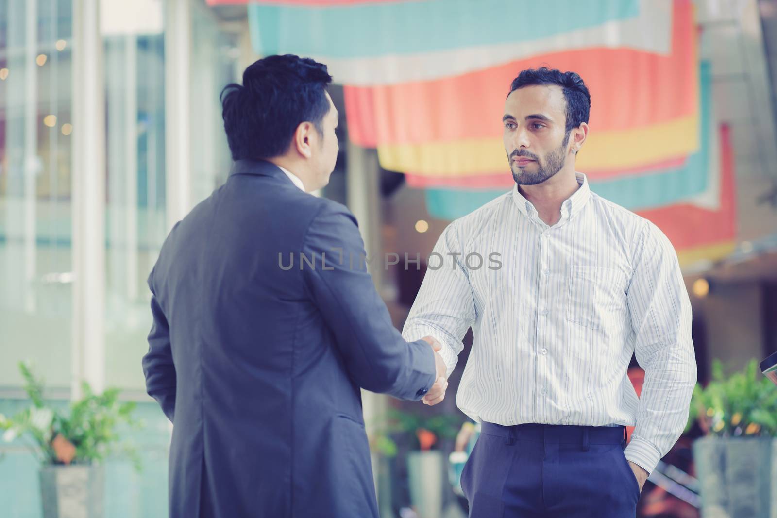 two businessmen shaking hands on outdoors.