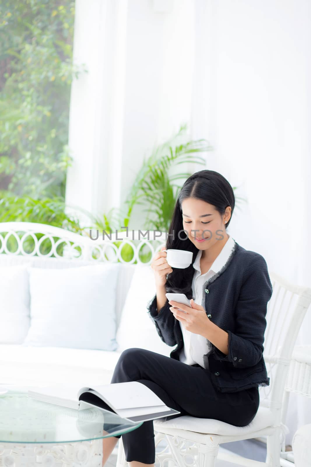 Young businesswoman asian sitting at table in coffee shop and looking phone.
