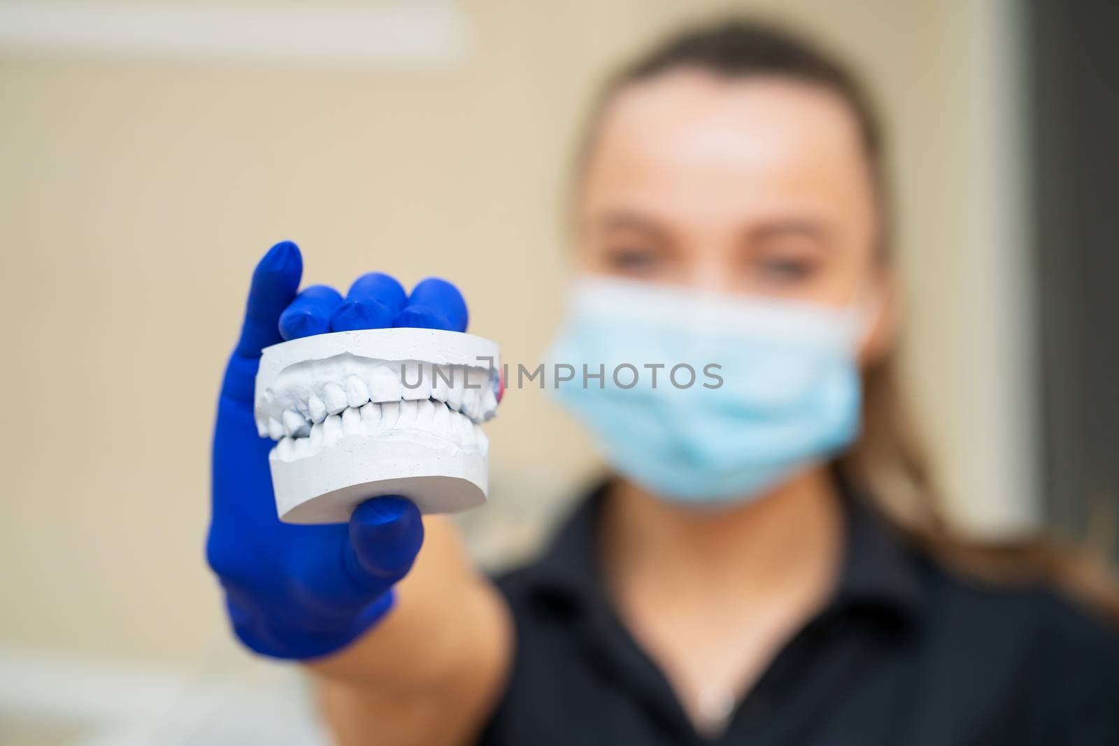 Beautiful girl professional doctor dentist orthodontist shows a plaster cast of the jaw.