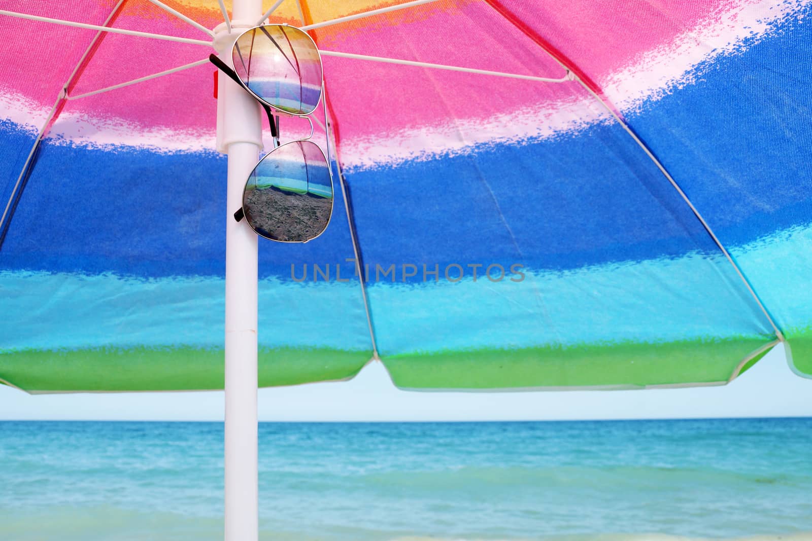 beach umbrella and sunglasses against the sea horizon and clear sky