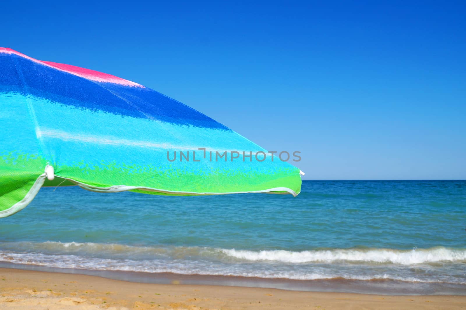 beach umbrella against the sea horizon and clear sky, copy space. by Annado