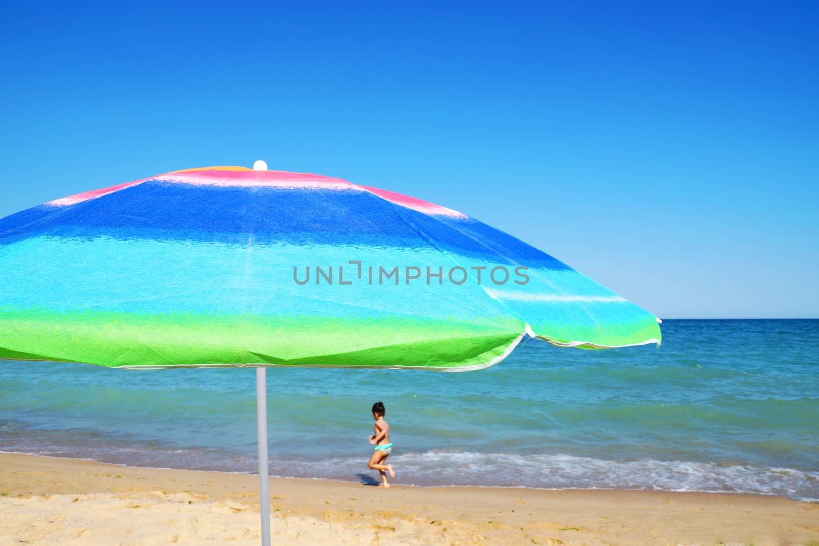 beach umbrella and sunglasses against the sea horizon and clear sky, copy space. by Annado