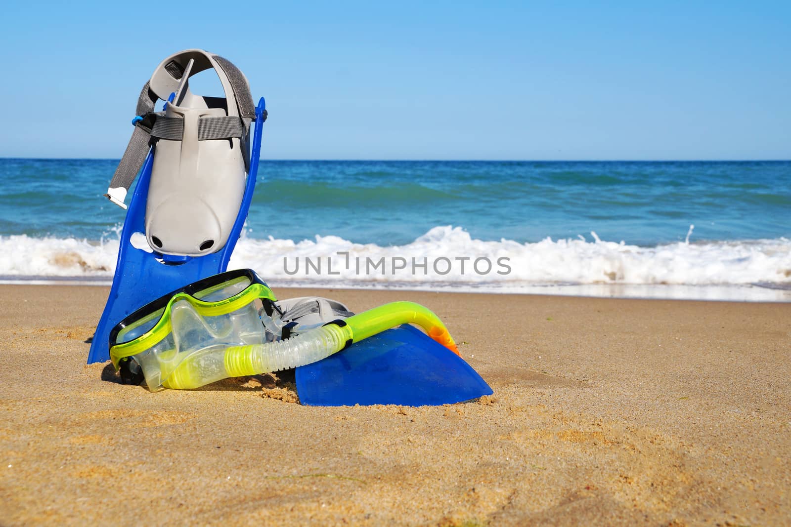 flippers and mask for swimming on the sand against the background of the sea and clear sky, copy space