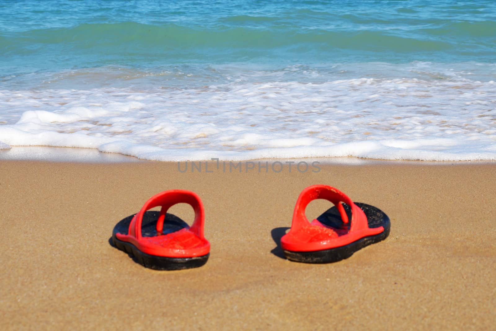 red beach slates on an empty sandy beach near the sea waves. by Annado