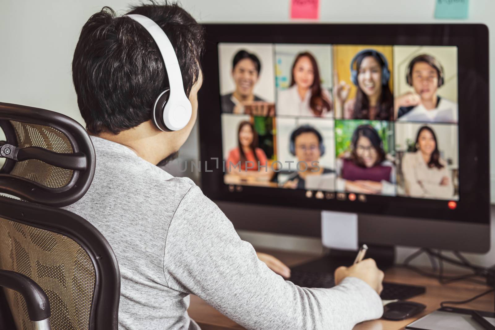 Rear view of Asian man working and online meeting via video conf by Tzido