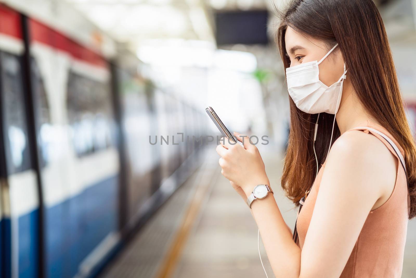 Young Asian woman passenger wearing surgical mask and listening by Tzido
