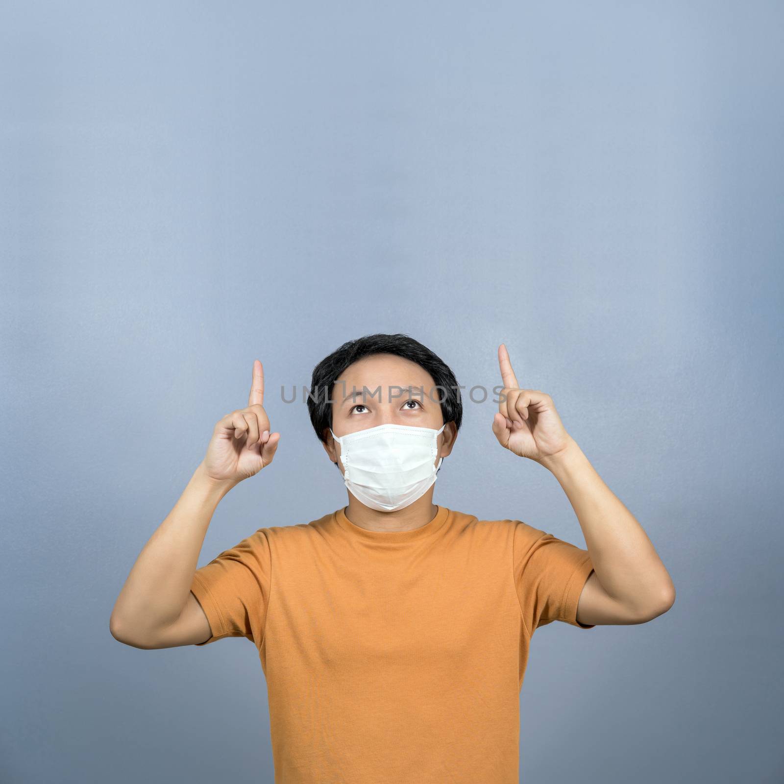 Asian man wearing face surgical mask pointing and presenting som by Tzido