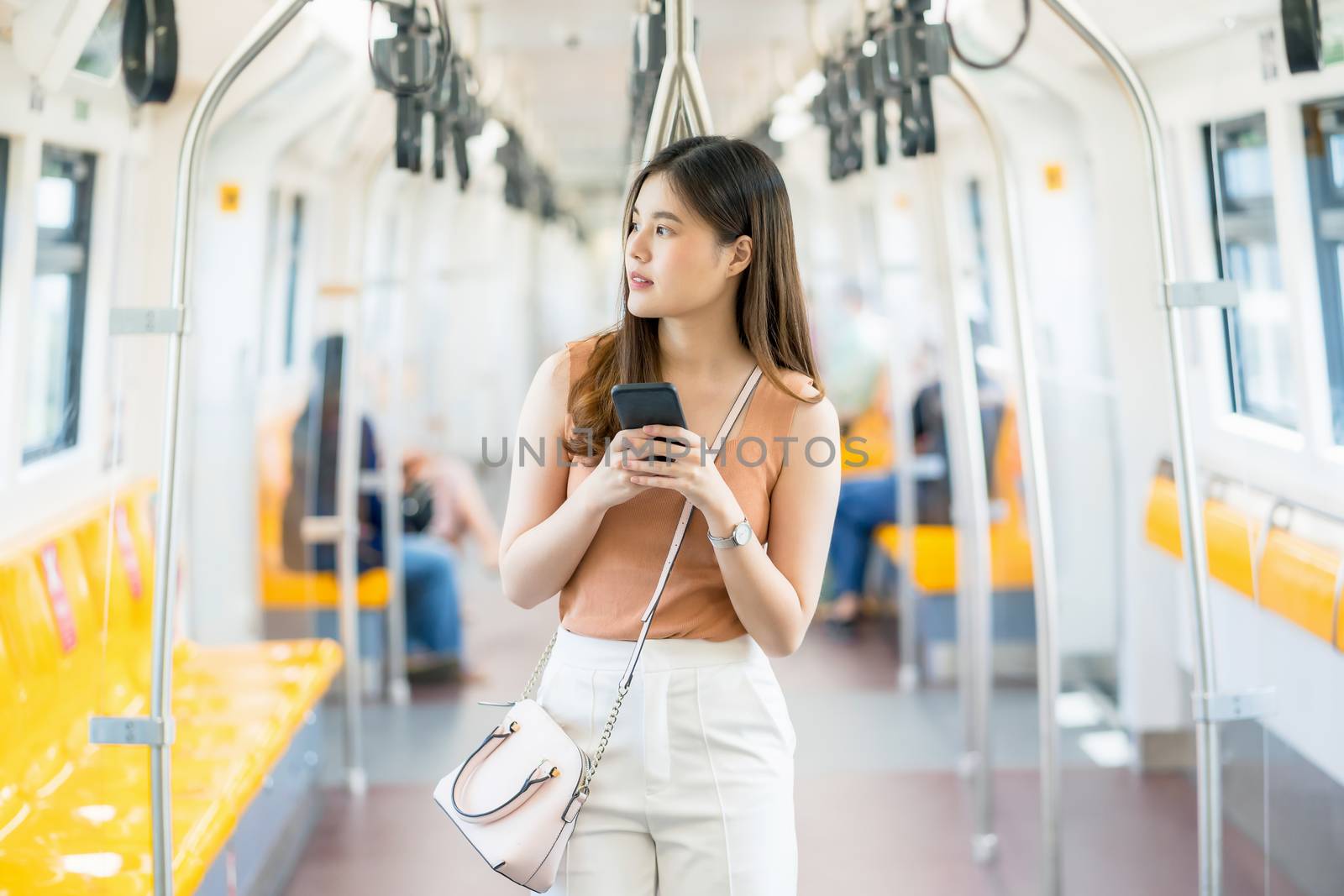 Young Asian woman passenger using smart mobile phone and looking by Tzido