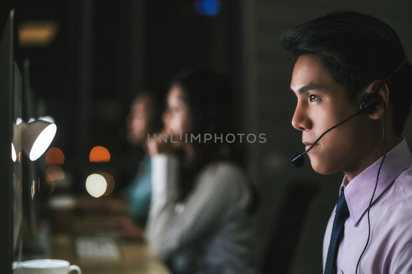 Closeup Asian Male customer care service over business woman working hard late in night shift at office,call center department,worker and overtime,team work with colleagues for success, 7 day 24 hour