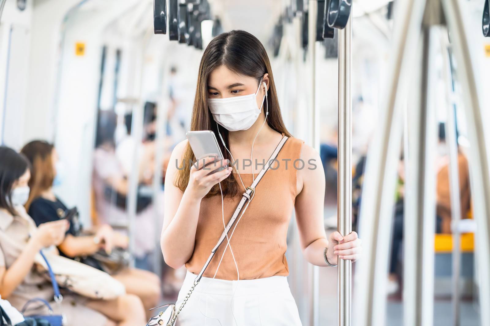 Young Asian woman passenger wearing surgical mask and listening by Tzido