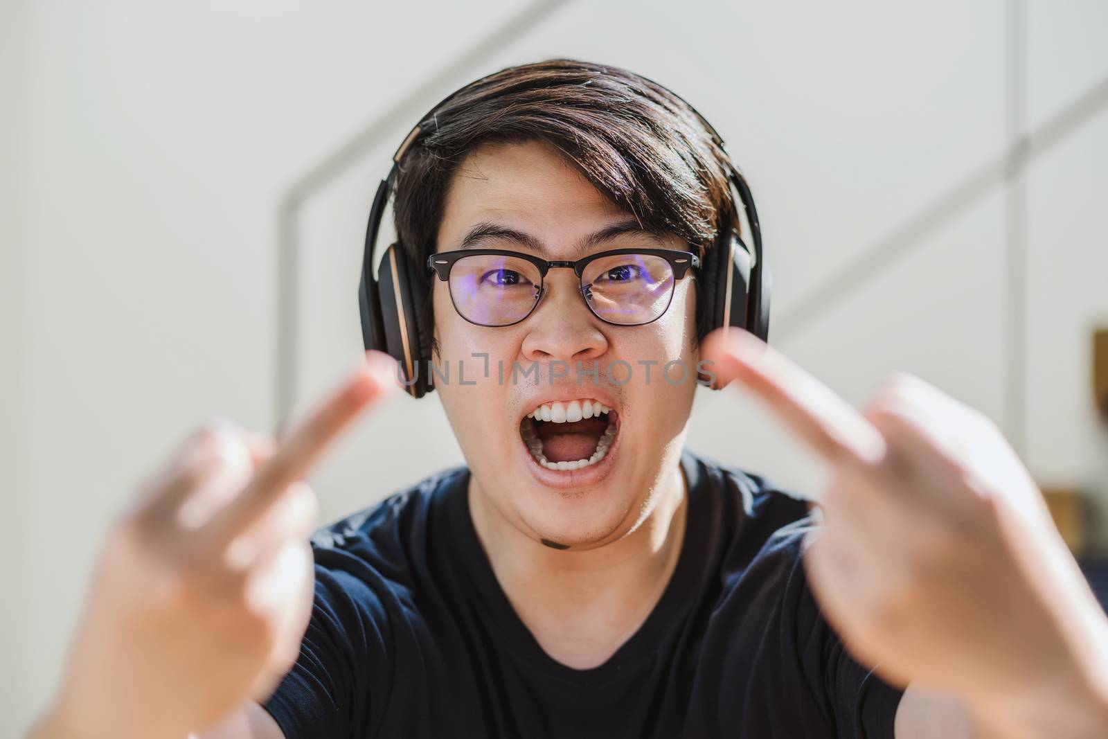 Asian Man showing thumbs up sign Fuck when he angry in stay from home at covid19 pandemic, serious expression when work from home, doing fucking off to camera, social distancing concept