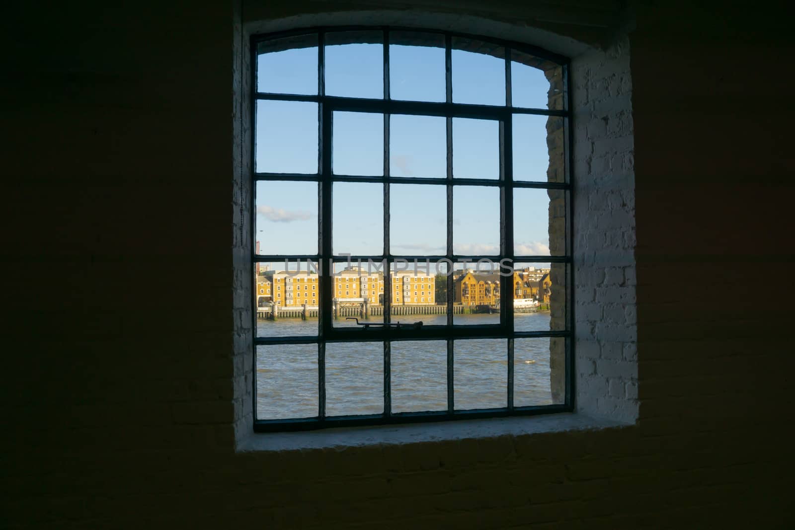 View through old multipane window to buildings on other side River Thames through old wharf building windows. Wapping, London buildings Metropolitan Wharf.