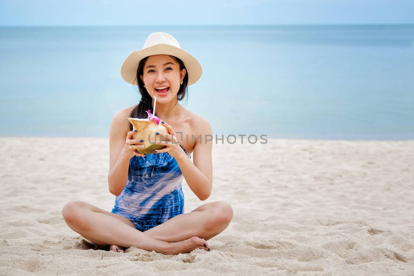 
Happy woman with fresh coconut water on the beach