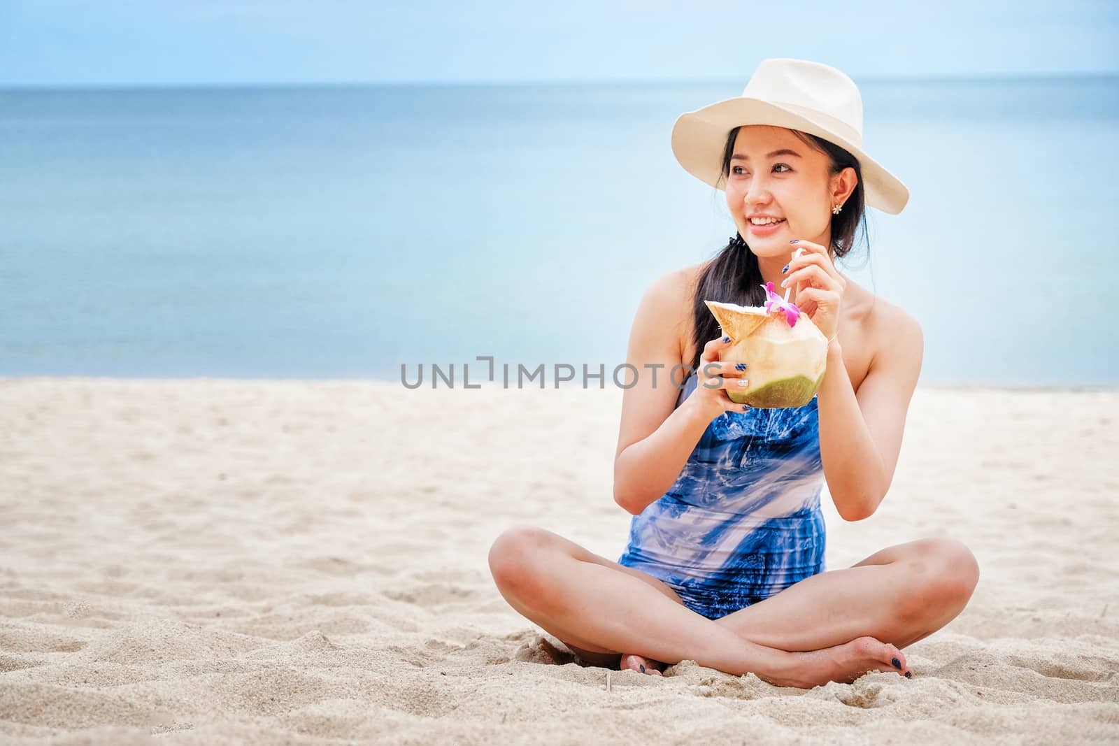 
Happy woman with fresh coconut water on the beach