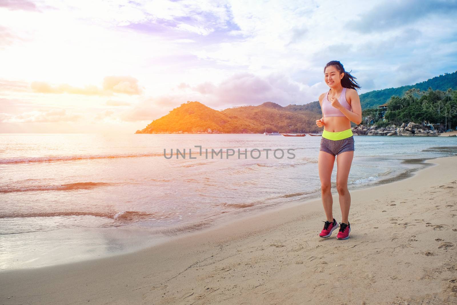 Runner woman running on beach in sunrise by Surasak