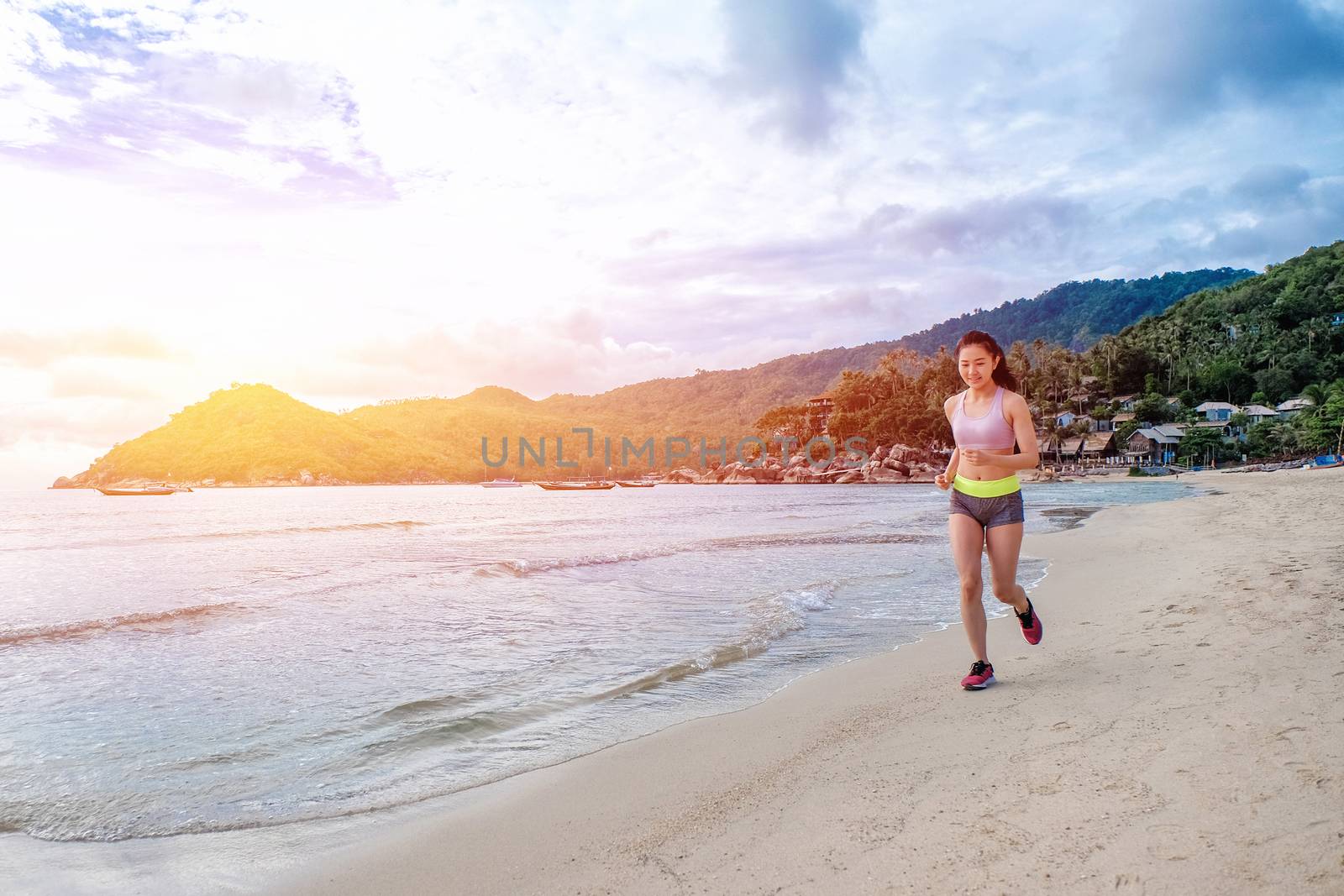 Runner woman running on beach in sunrise
