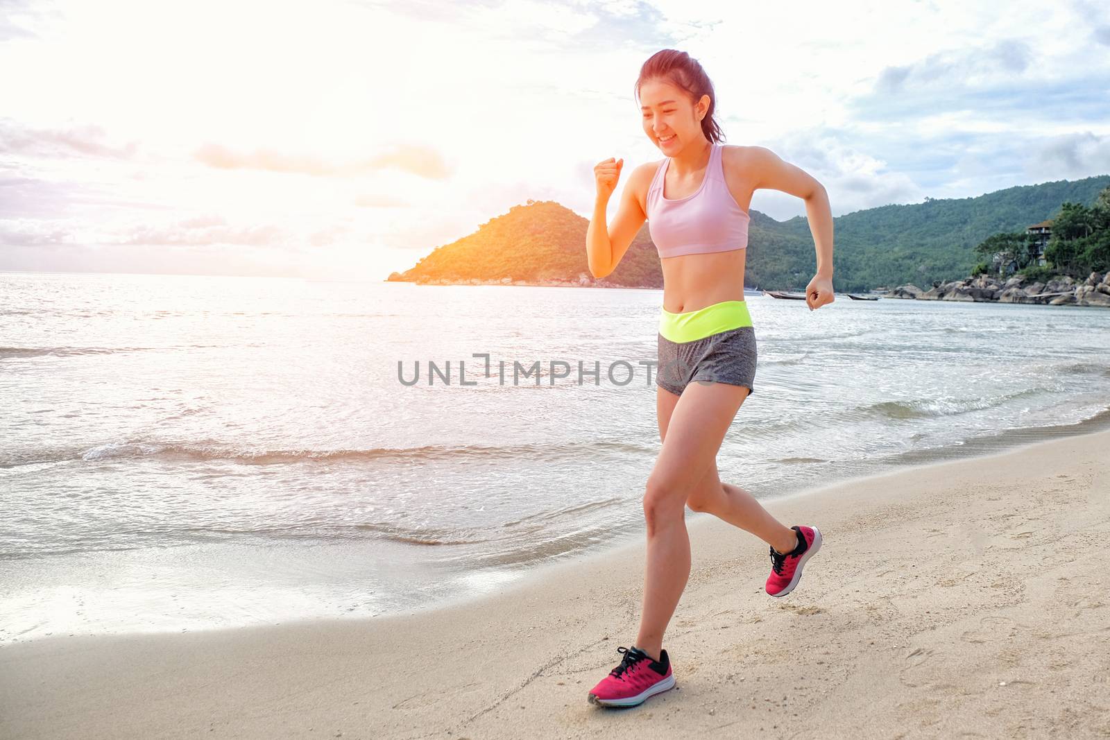 Runner woman running on beach in sunrise