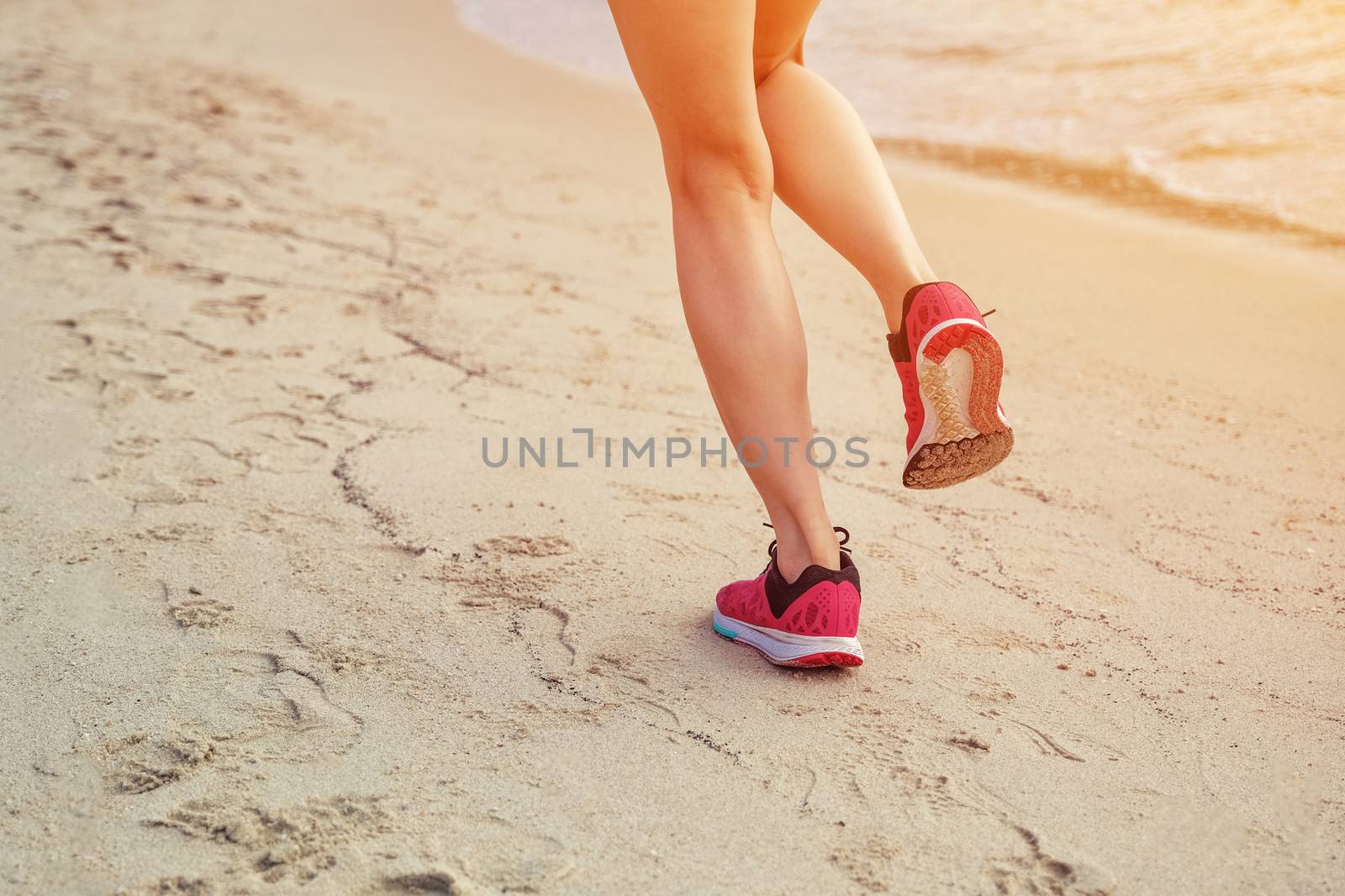 Runner woman running on beach in sunrise by Surasak