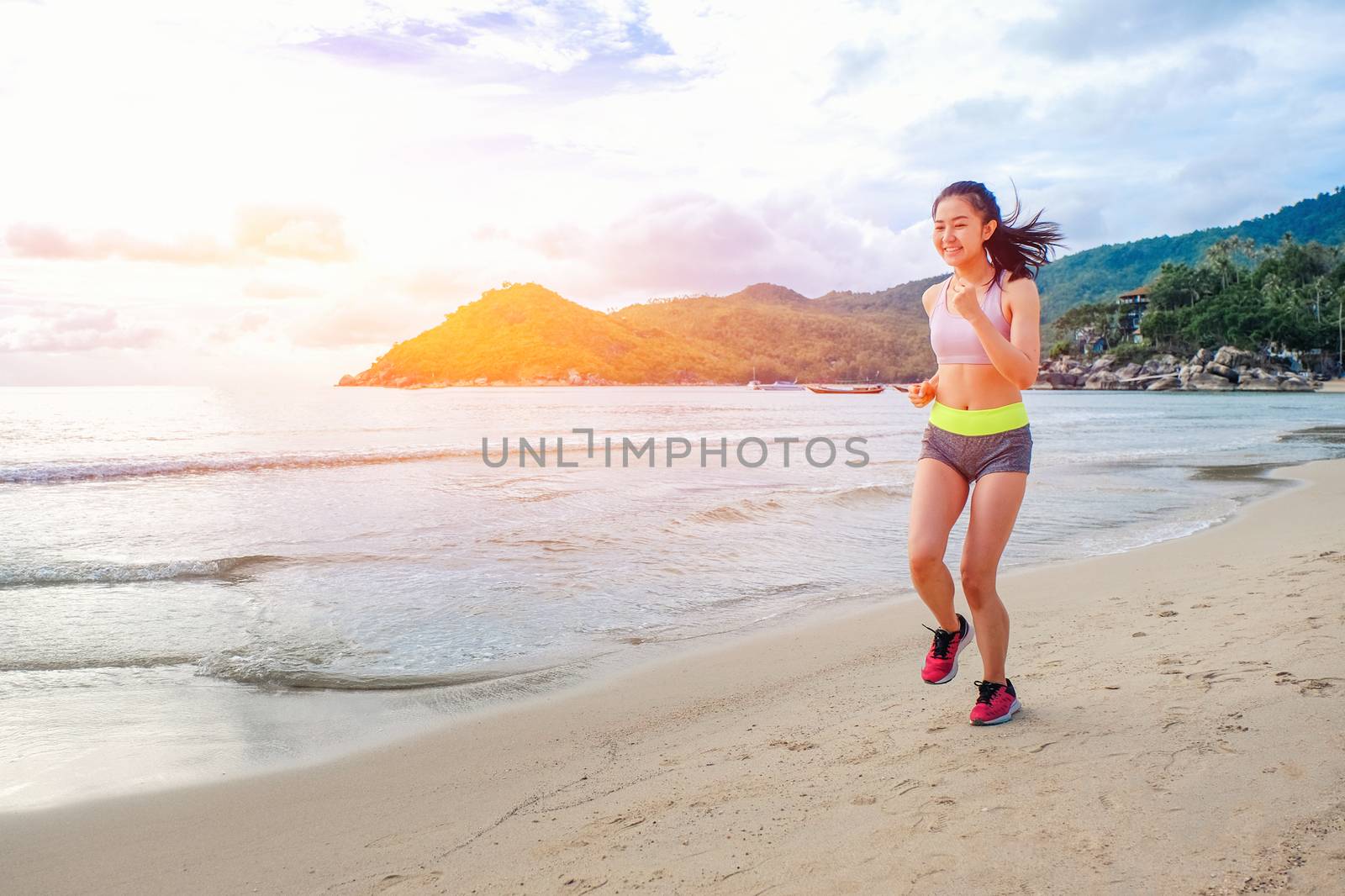 Runner woman running on beach in sunrise by Surasak