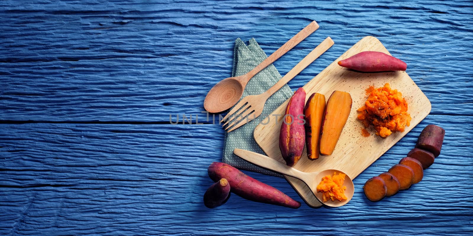 Sweet Potato on wooden cutting board and blank space for text on the left side with blue wood background