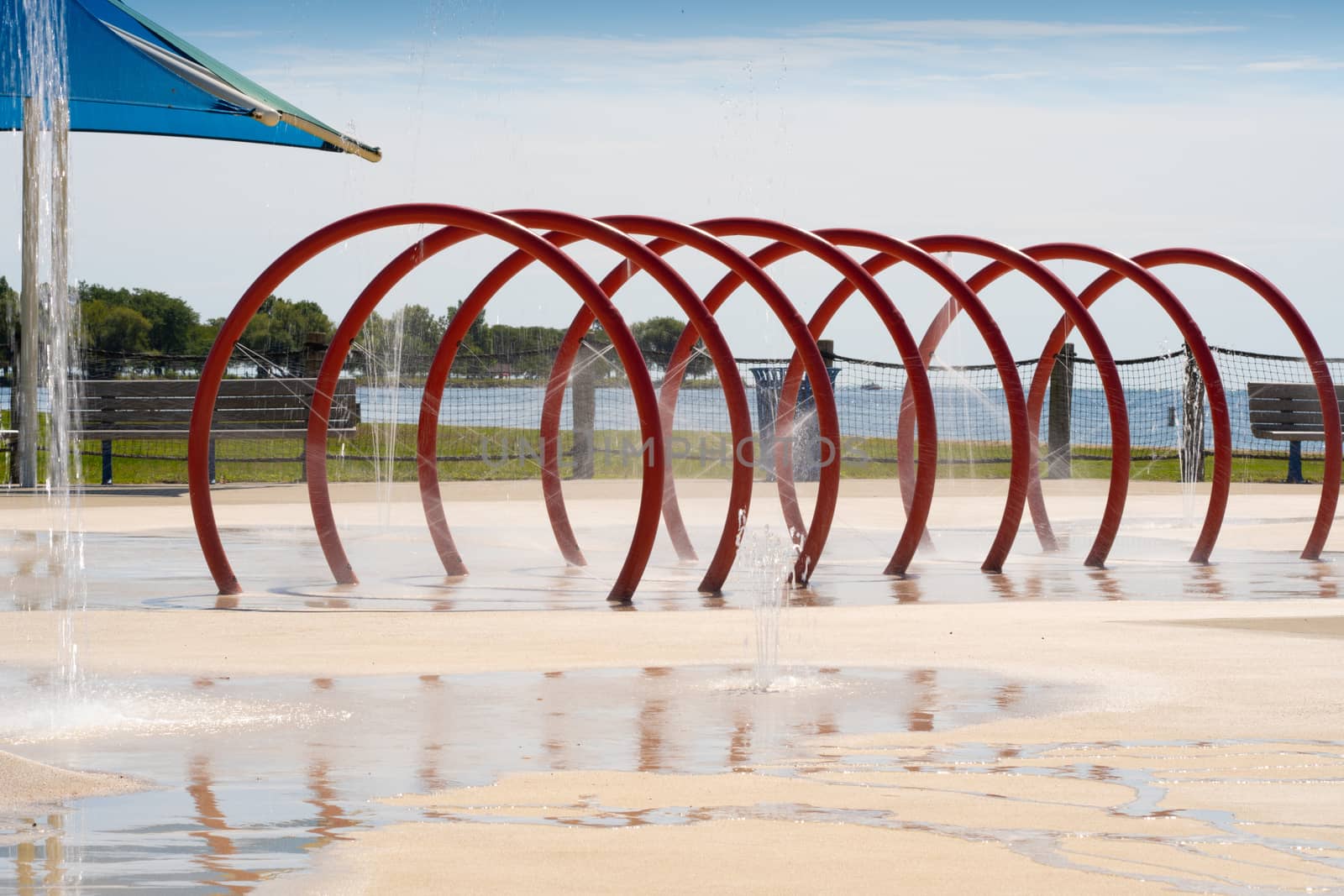 Colorful spraypad tunnel with beach in the distance by jen_ishayoga