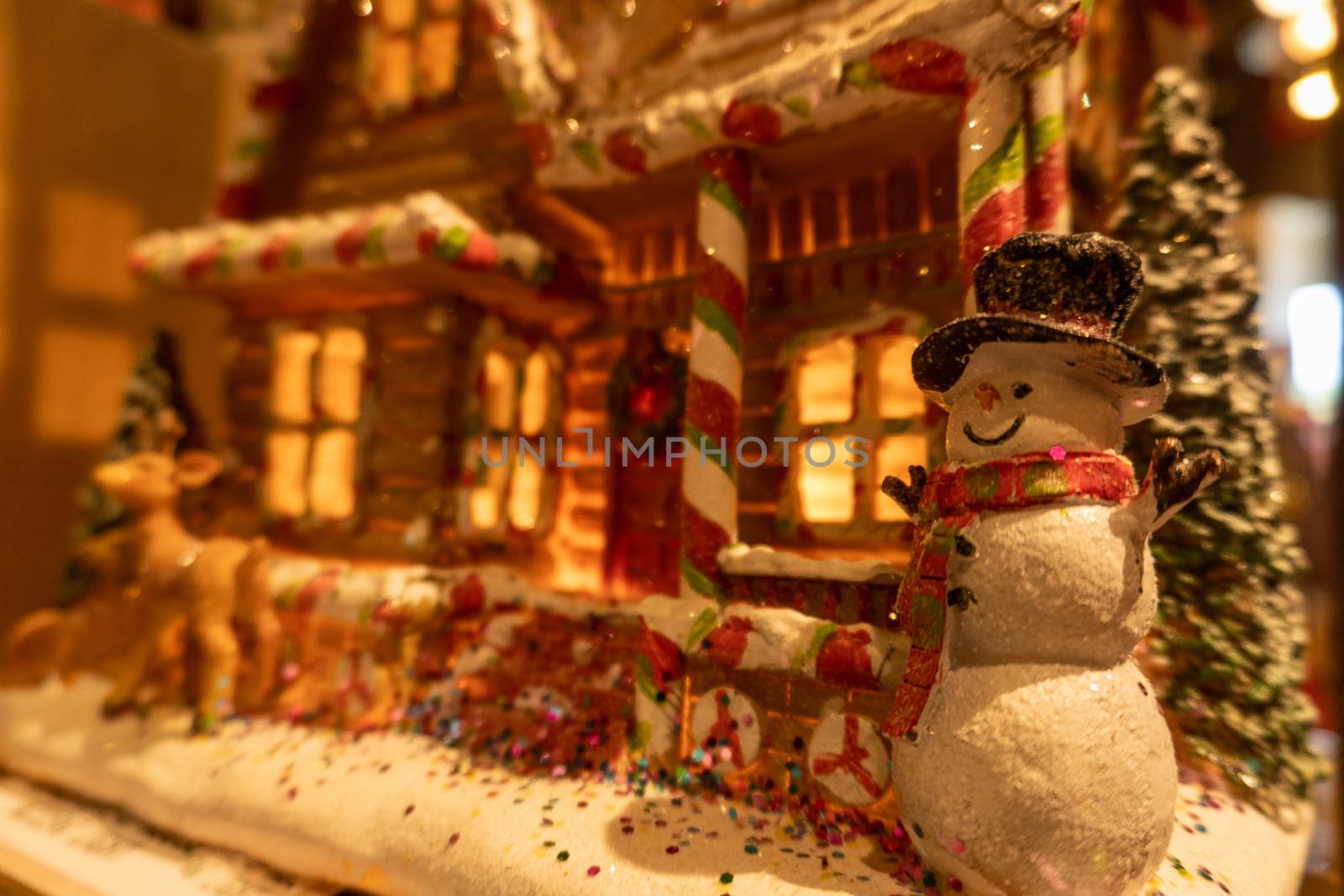 Closeup of a happy snowman in front of a colorful gingerbread house