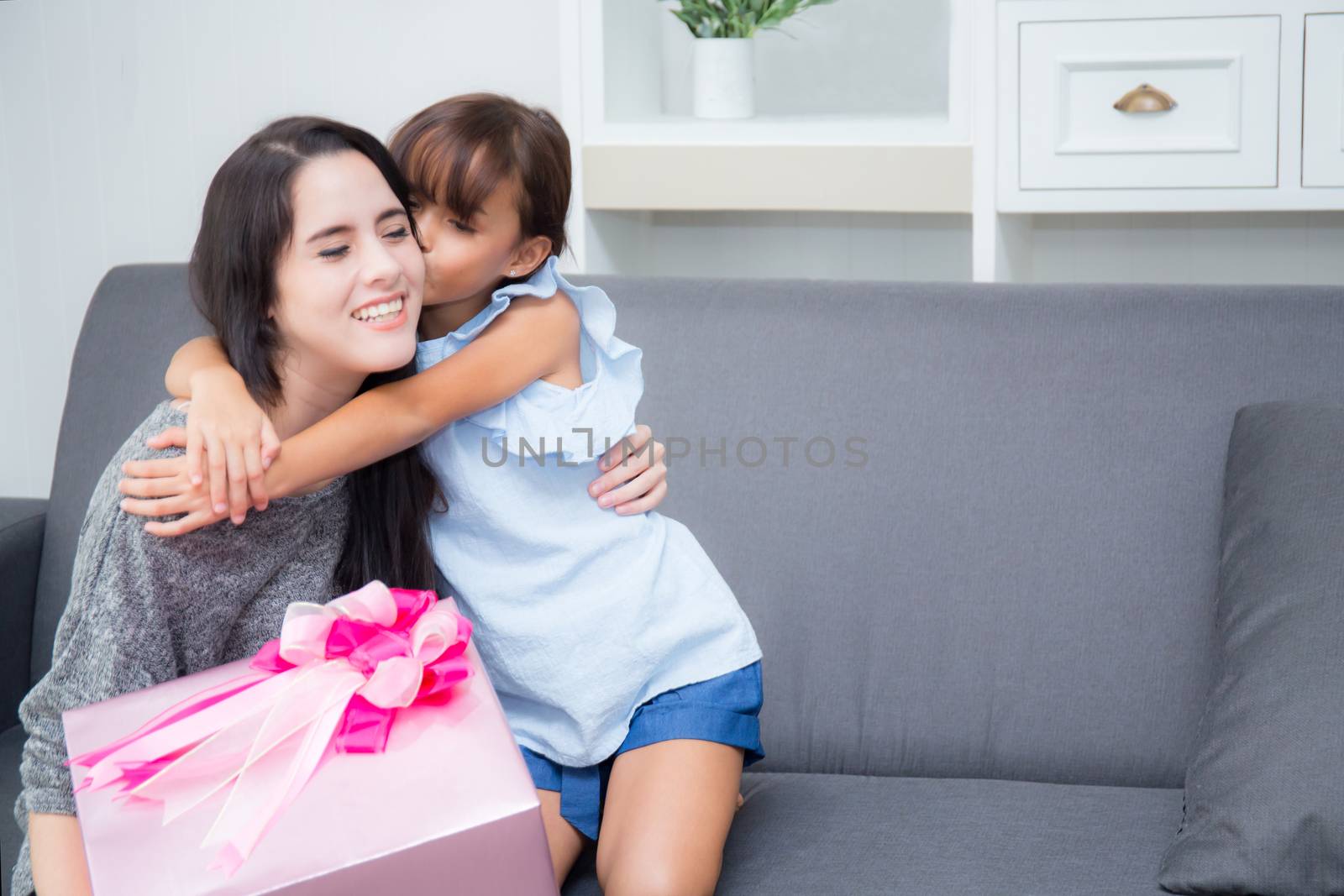 happy of mother and daughter asian with gift with pink ribbon and daughter kissing mother, Happy family concept. Happy mother's day.