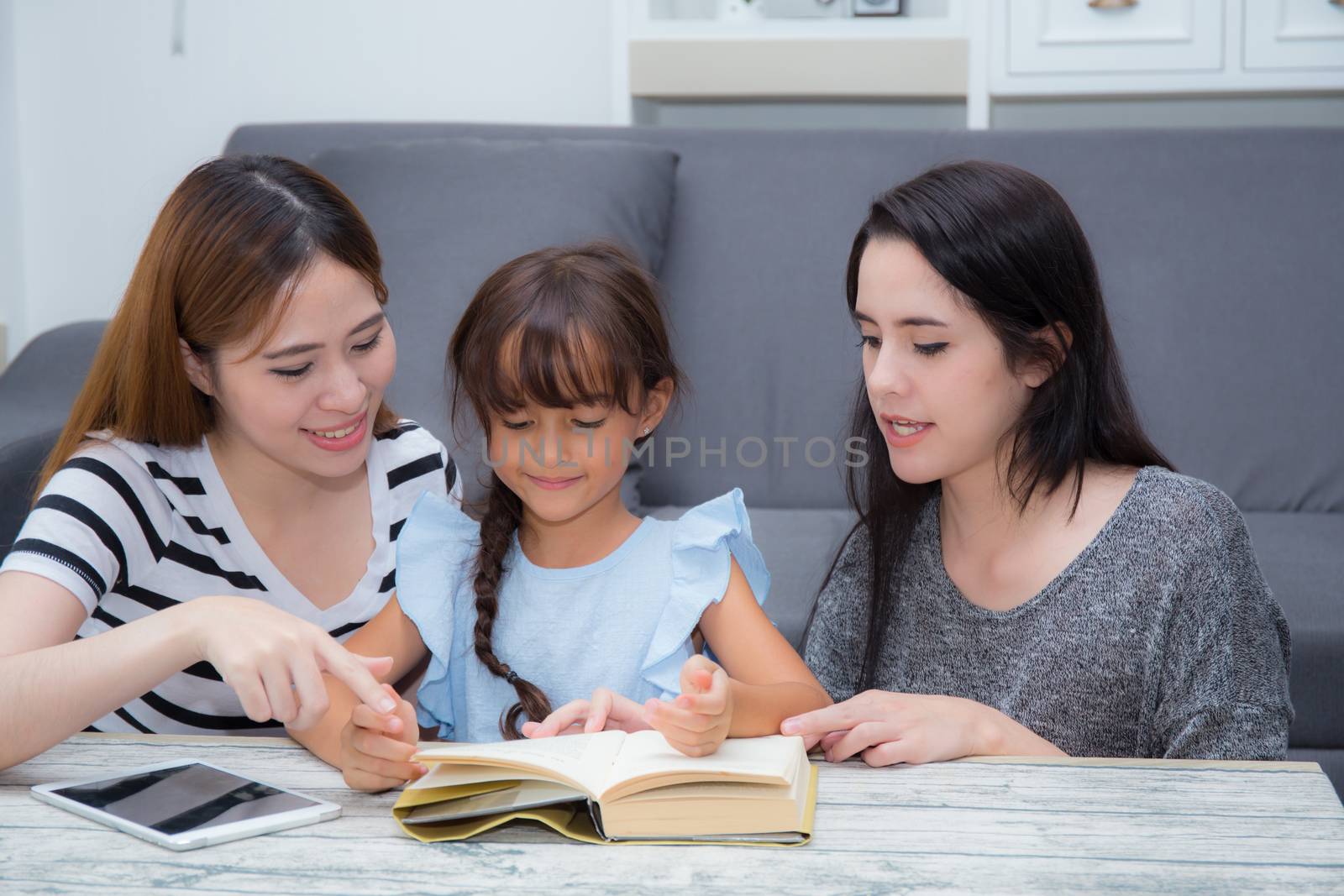 happy family mother, aunt, freind and daughter teaching read a book at home.