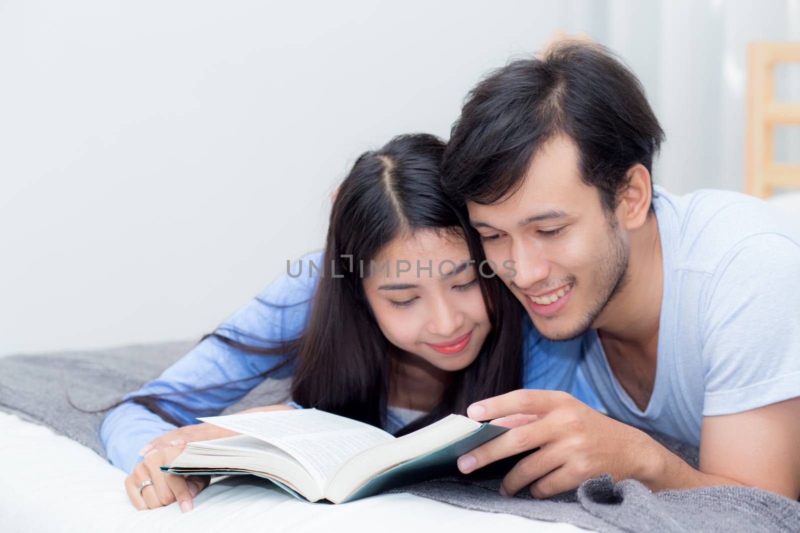 Couple reading a book together in bedroom on the morning with happiness.