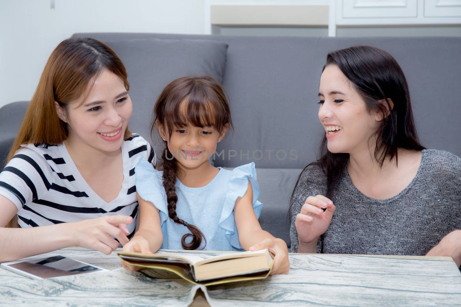 happy family mother, aunt, freind and daughter teaching read a book at home.