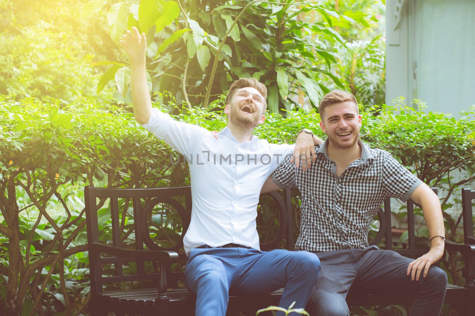Two friends men talking standing in a garden.