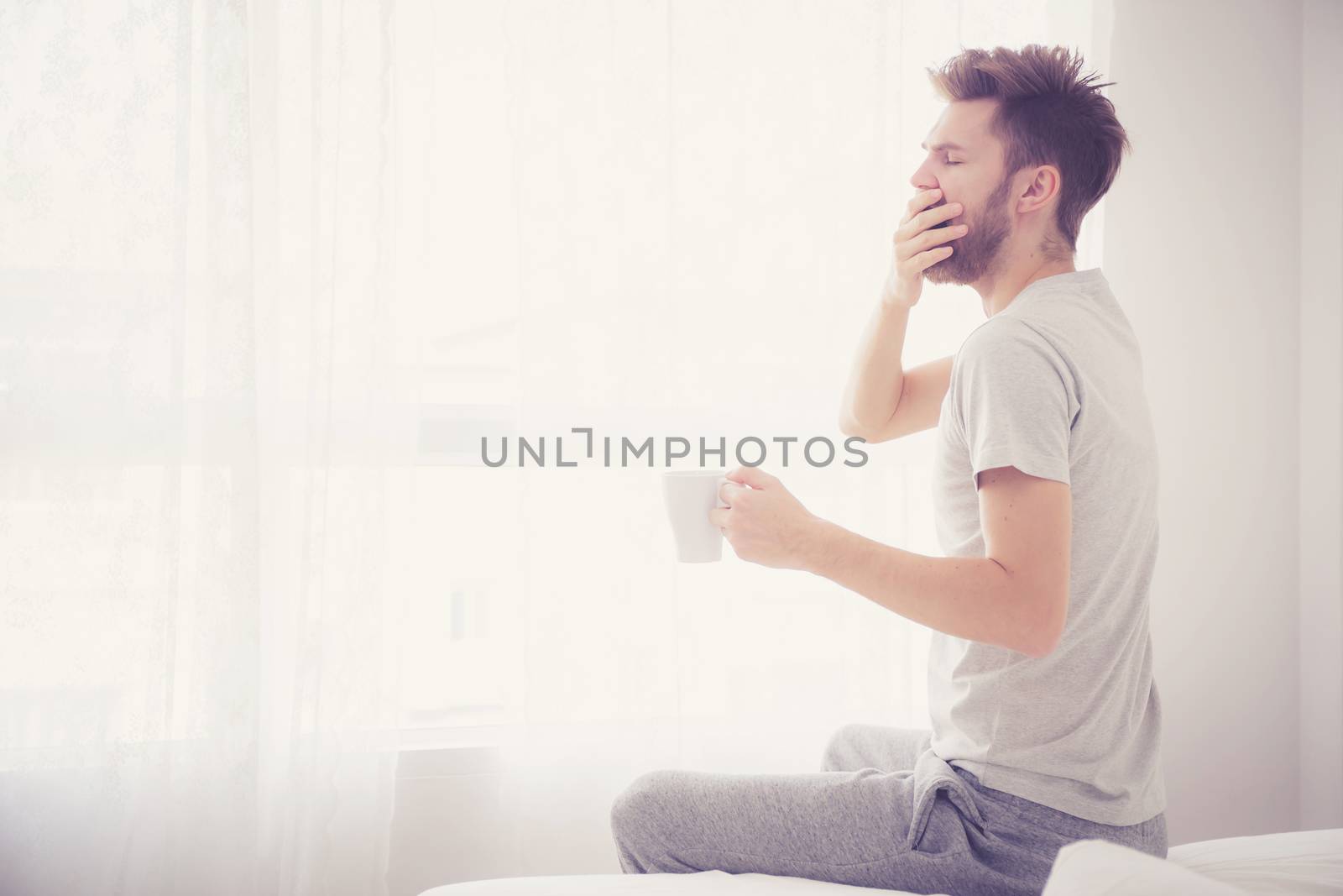 Lifestyle portrait of bedroom concept: Man holding a cup of coff by nnudoo