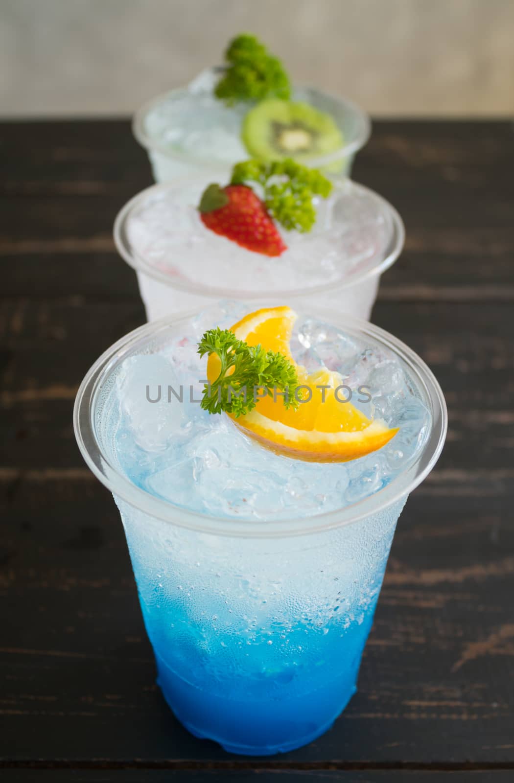 Blue Red Green Italian Soda Cold Beverage and Lemon Strawberry Kiwi Fruit and Parsley. Blue Red Green Italian Soda Cold Beverage on wood table for food and drink category