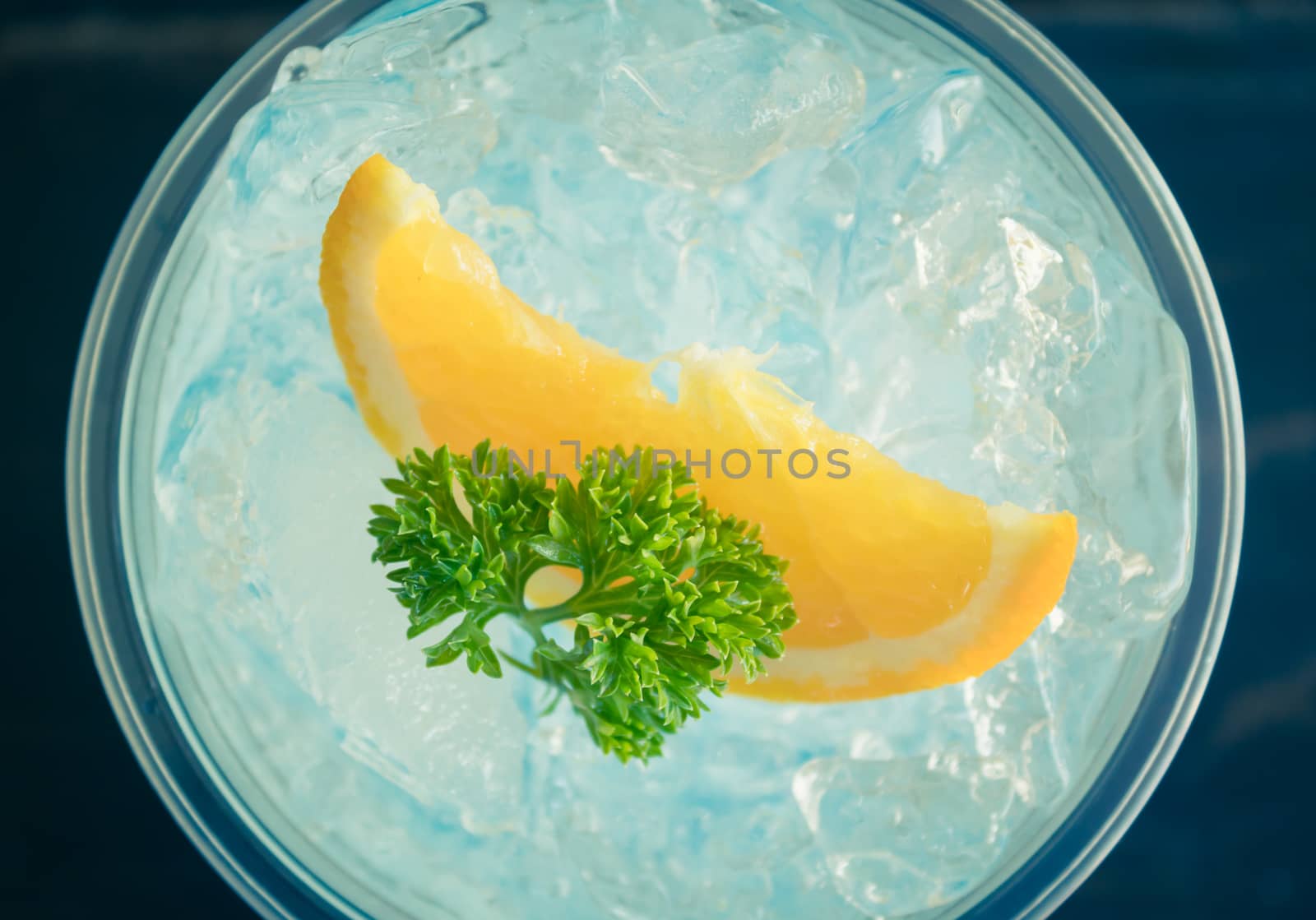 Blue Italian Soda Cold Beverage and Lemon Fruit and Parsley. Blue Italian Soda Cold Beverage with Lemon fruit and ice in glass on wood table for food and drink category