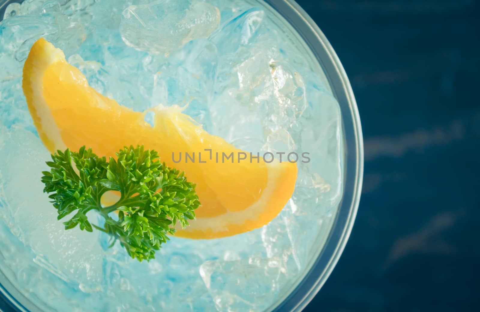 Blue Italian Soda Cold Beverage and Lemon Fruit and Parsley. Blue Italian Soda Cold Beverage with Lemon fruit and ice in glass on wood table for food and drink category