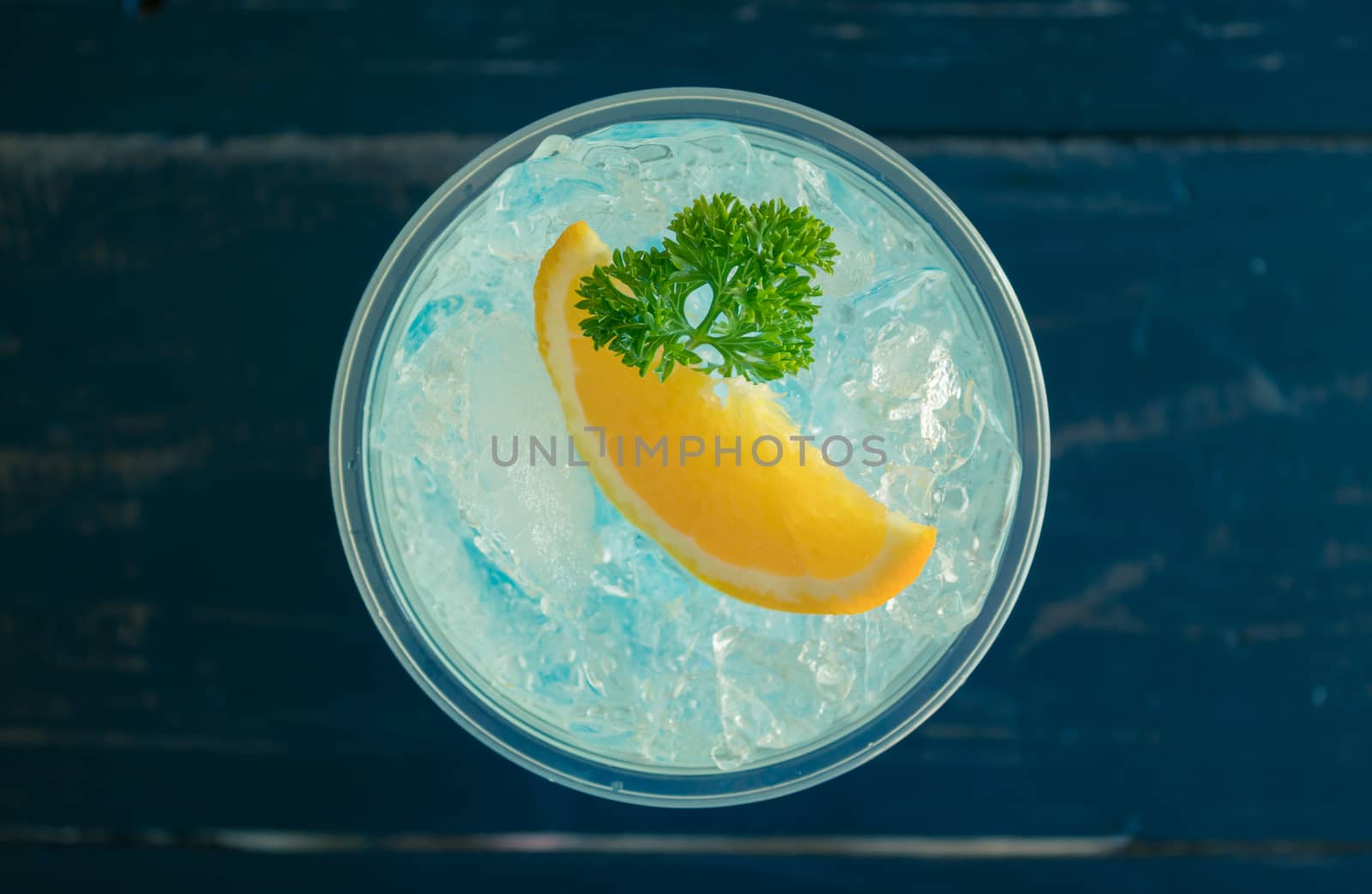 Blue Italian Soda Cold Beverage and Lemon Fruit and Parsley. Blue Italian Soda Cold Beverage with Lemon fruit and ice in glass on wood table for food and drink category
